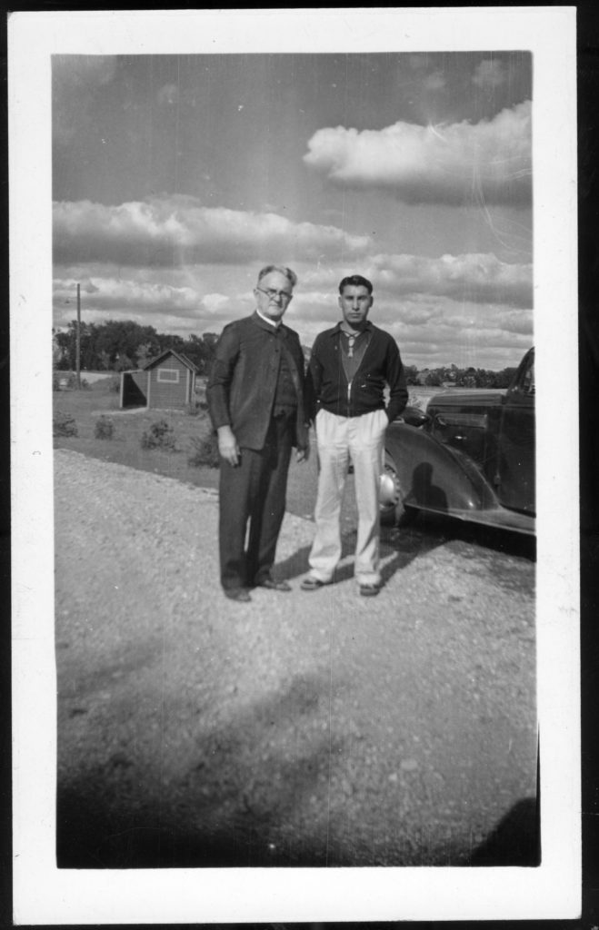 Young Cheyenne man with white man in a plain coat, on back it says “The big shot of the College” [from folder 108]